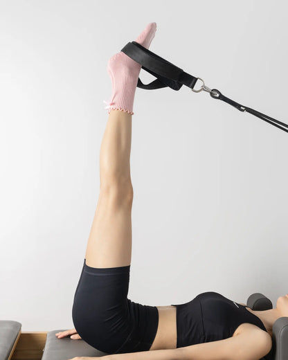 Legs extended on a reformer footbar wearing pink Tenduu Active grip socks